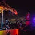 DJ at a tropical outdoor party with city Cartagena in the background