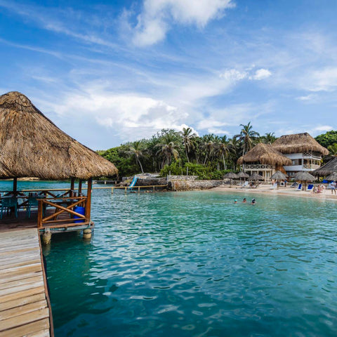 Tropical beach with thatched-roof huts and clear blue water