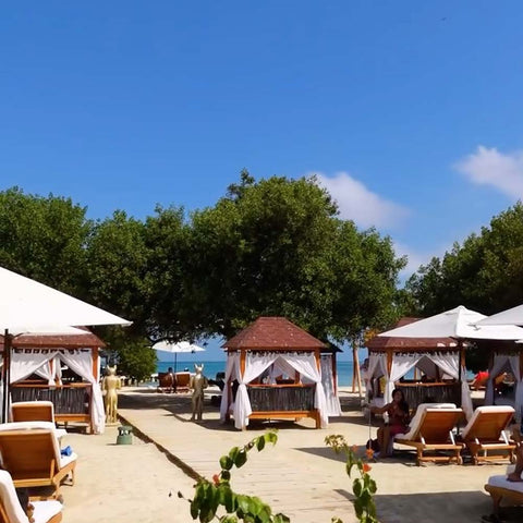 Panoramic view of Pao Pao Beach Club with sun loungers on the sand and blue ocean background.